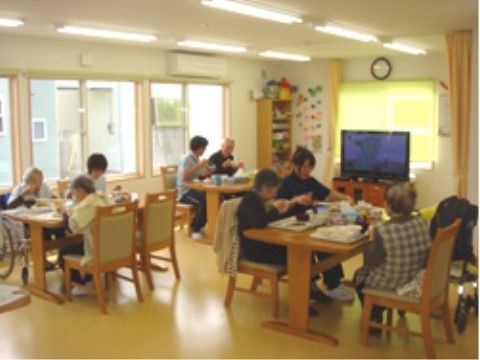 入居者様同士が向かい合い、隣り合って食事をしている。車椅子をご利用の入居者様も同じテーブルにつき一緒に食事を楽しんでいる。