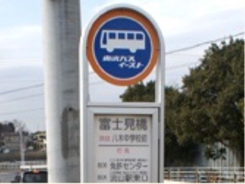 電柱の前に立てられた最寄りのバス停の写真である。歩道に白い柵が設置されており、奥には住宅街が見える。
