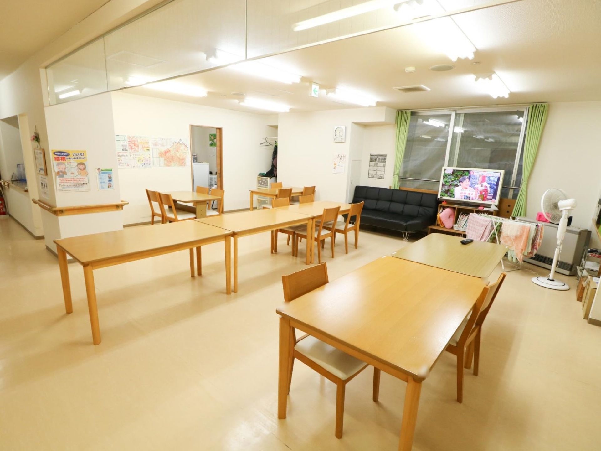 通路の一角が広くなっており、木製のテーブルや椅子がある。窓の近くに液晶テレビや黒いソファが置いてある。