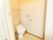 洋式便器が据えられているトイレスペースである。壁面にはペーパーホルダーのほかに、Ｌ字型の手すりやナースコールが設置されている。