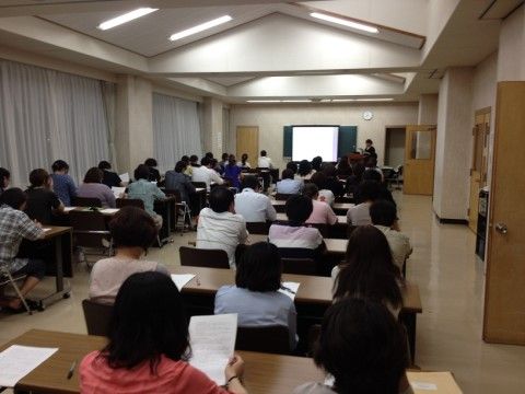 3人掛けの机が多く並び、講義を受けている多数の出席者