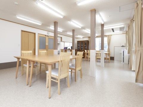 蛍光灯が設置され、明るい木目調のテーブルセットが置かれた共有スペース