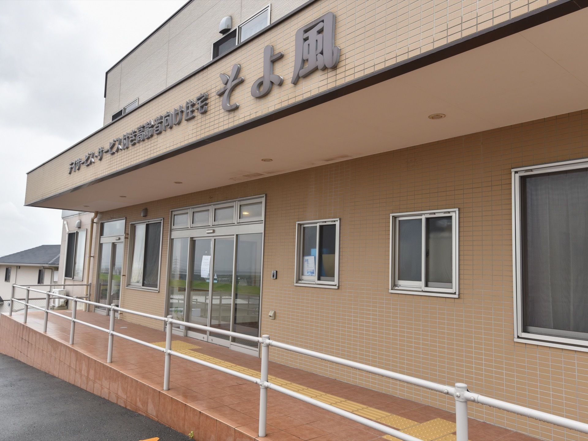 2階建ての施設の屋根部分には大きく施設名が書かれている。屋根は手すりが付いたスロープの上についている。