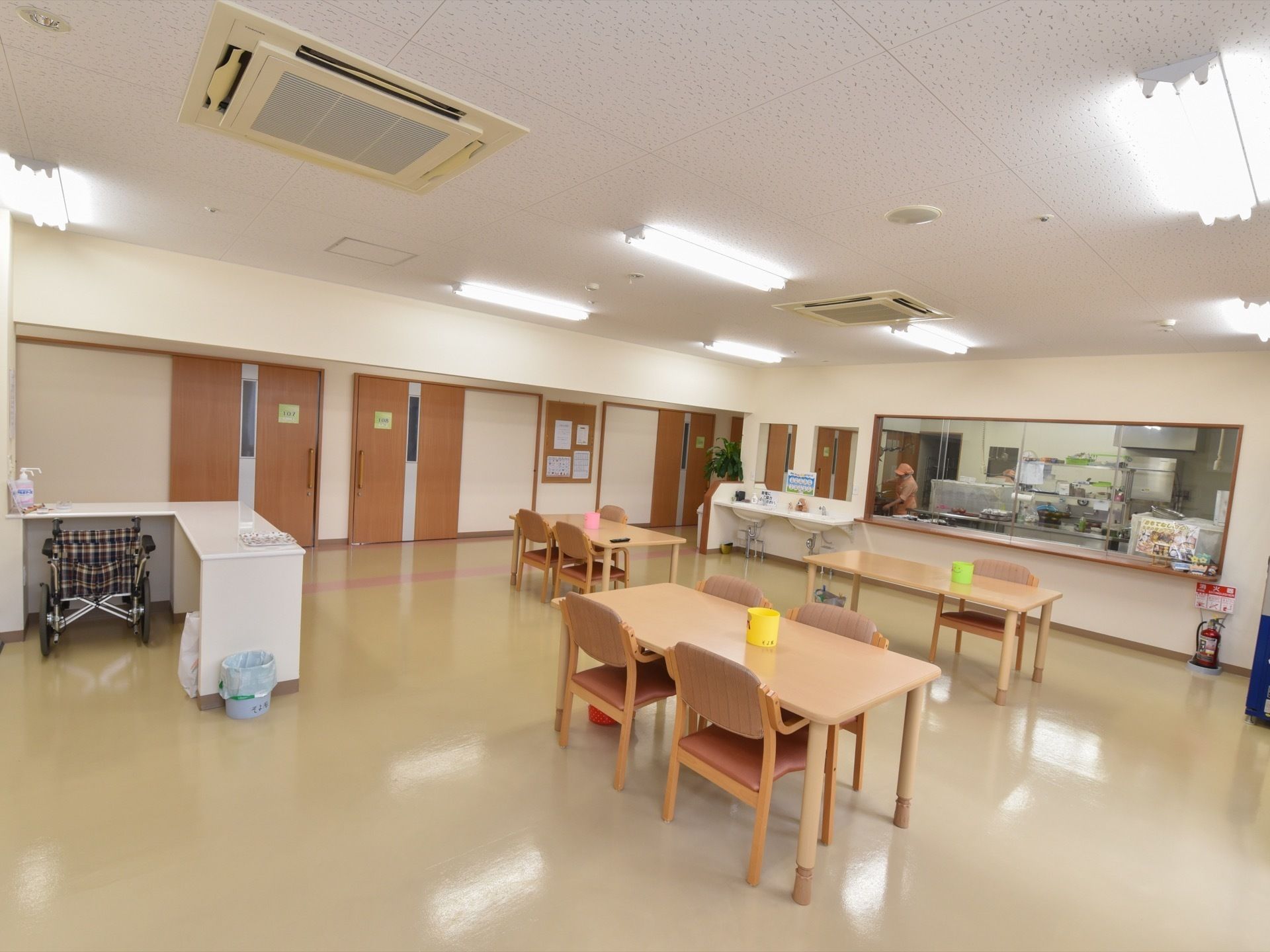 食堂には茶色いテーブルが3台、背もたれとひじ掛け付きの椅子が数脚並べられている。カウンター横には洗面台が2台ある。