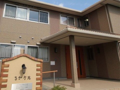 施設看板と屋根付きのポーチを完備した2階建て施設の外観