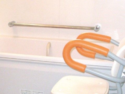 バスチェアーが設置され手すりが壁と浴槽内に取り付けられている浴室