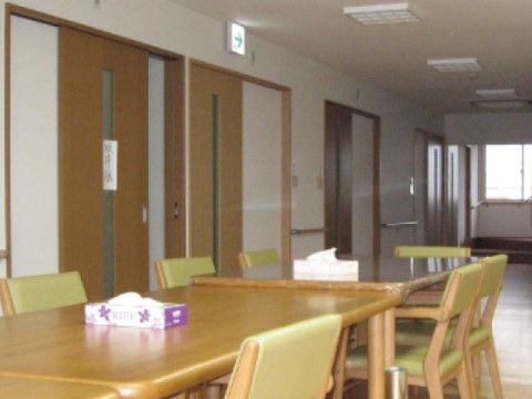 居室前の廊下に設置されたグリーン系のシート面が椅子のテーブルセット