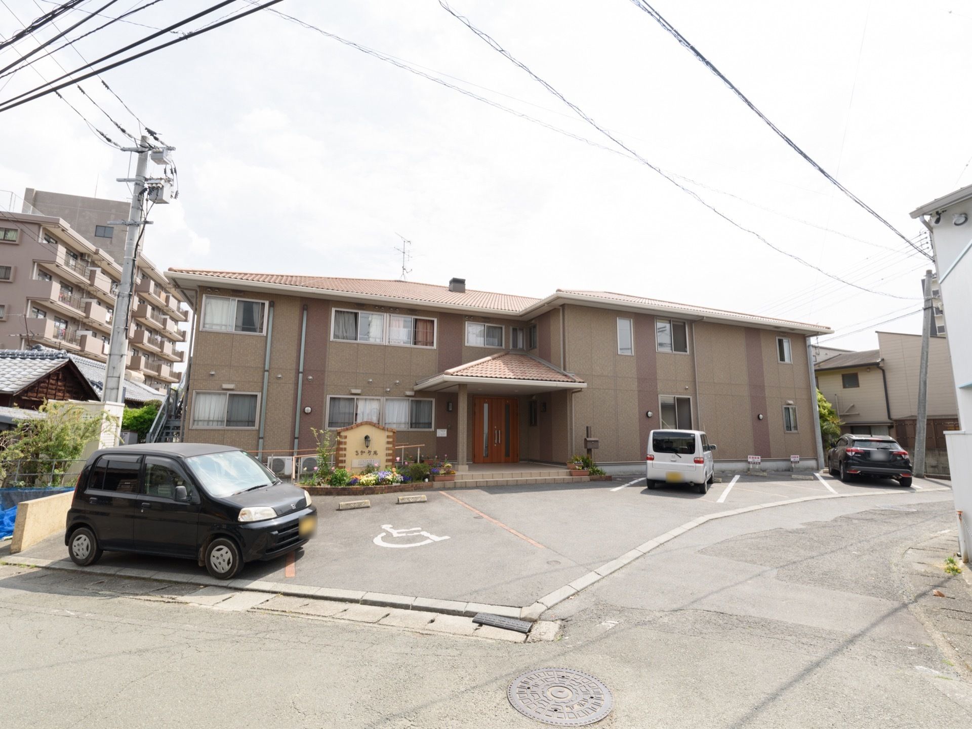 二階建ての建物で、敷地内手前に駐車場がある。玄関ポーチの横に施設の看板があり、その周りは花壇になっている。