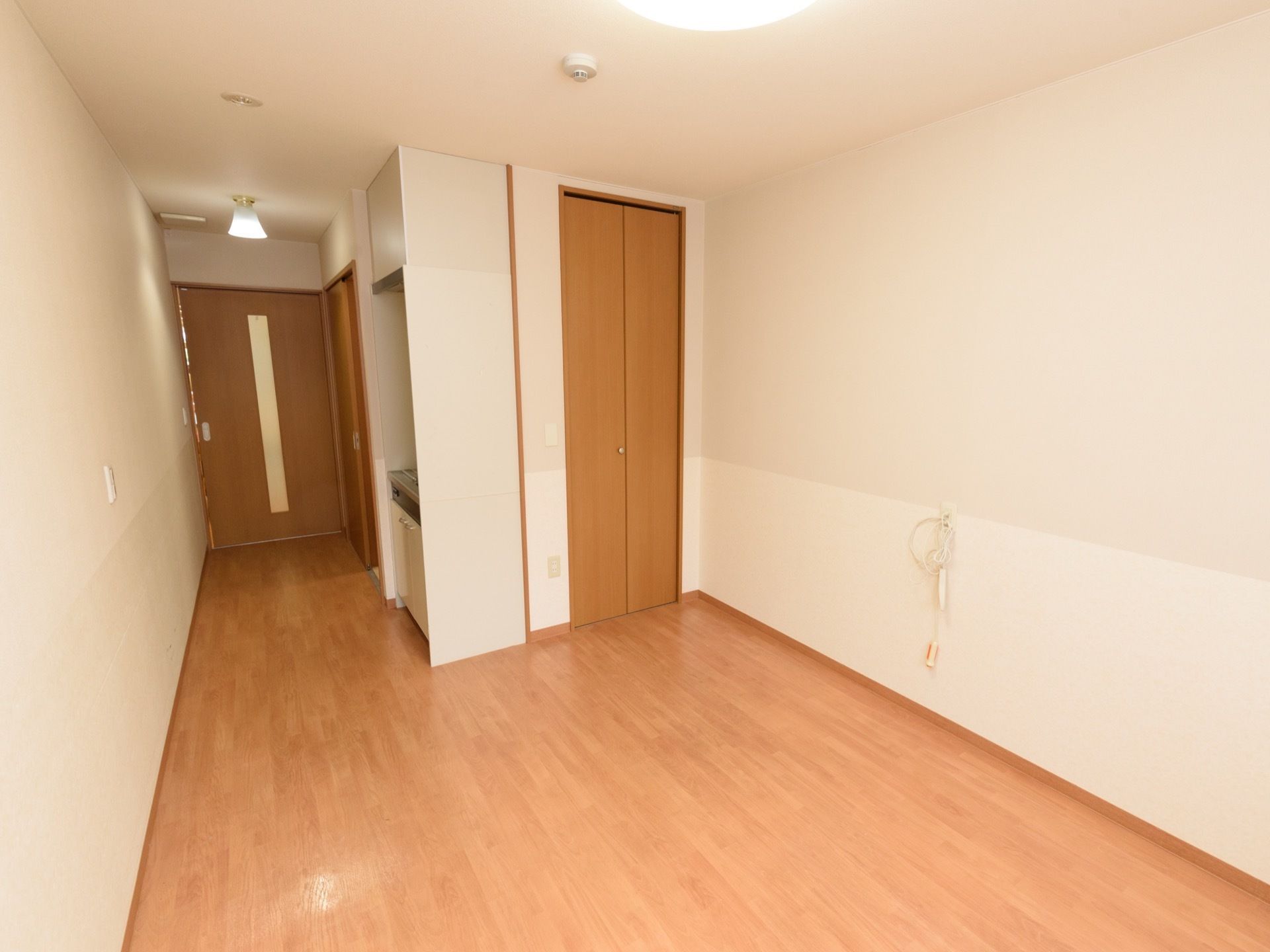 クローゼットの手前の壁に、緊急呼び出しブザーが設置されている。ミニキッチンやトイレがある。居室のドアはスライドドアである。