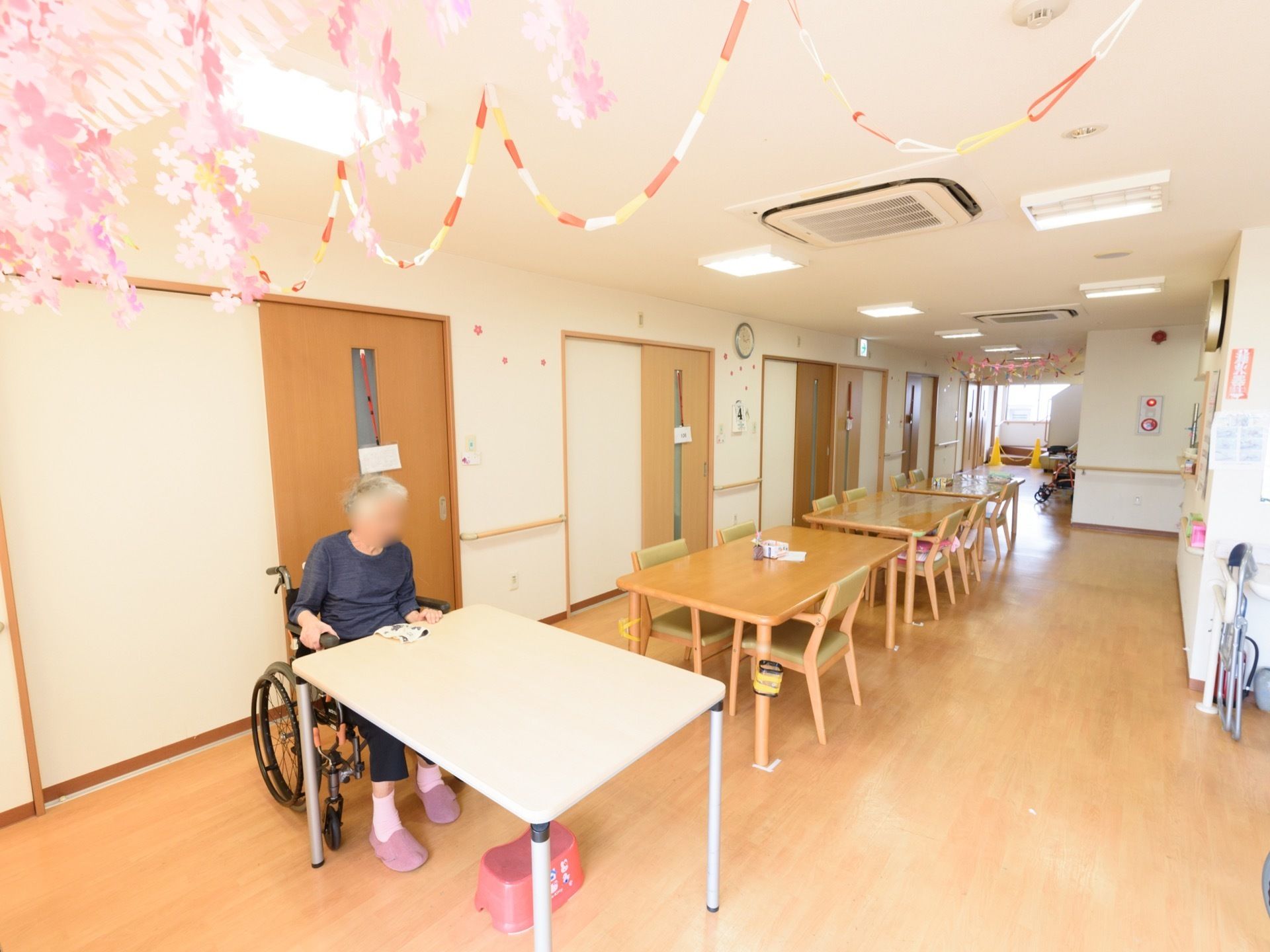 奥に長い形の食堂スペースである。天井や壁には、折り紙などで作られたきれいな色の飾り付けがされている。