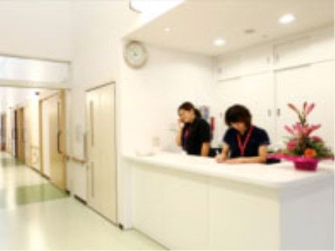 居室前の廊下に設けられたスタッフステーションで作業する２名の女性スタッフ