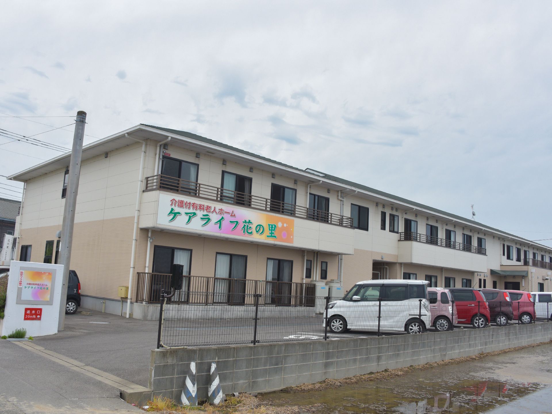 2階部分のベランダには、ピンクやオレンジ色が多く使われ、遠くからでもはっきりとわかる緑の文字で施設名が書かれている。