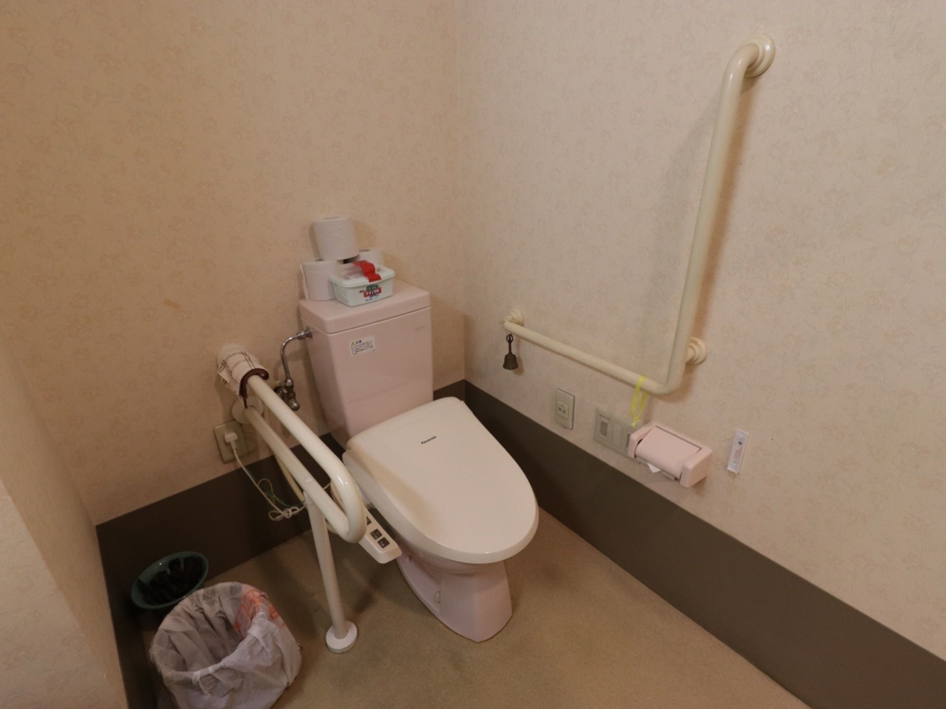 随所に手すりが付いている。ナースコールや呼び鈴がついている。温水洗浄便座が設けられている。オムツなどを捨てられるゴミ箱がある。