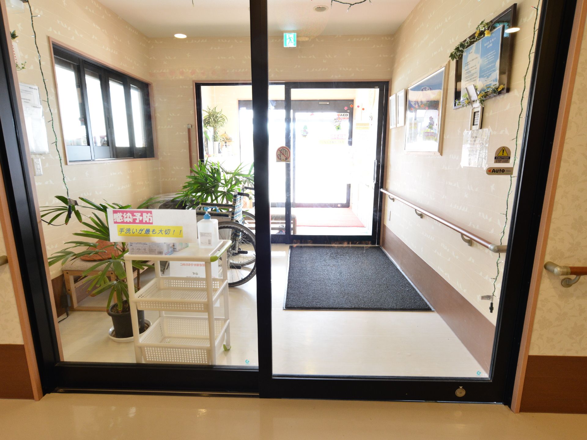 正面玄関の扉は3つあり、それら全てガラスの引き戸になっている。扉と扉の間には植物の植木鉢が置かれ、日差しが差し込み明るい空間である。