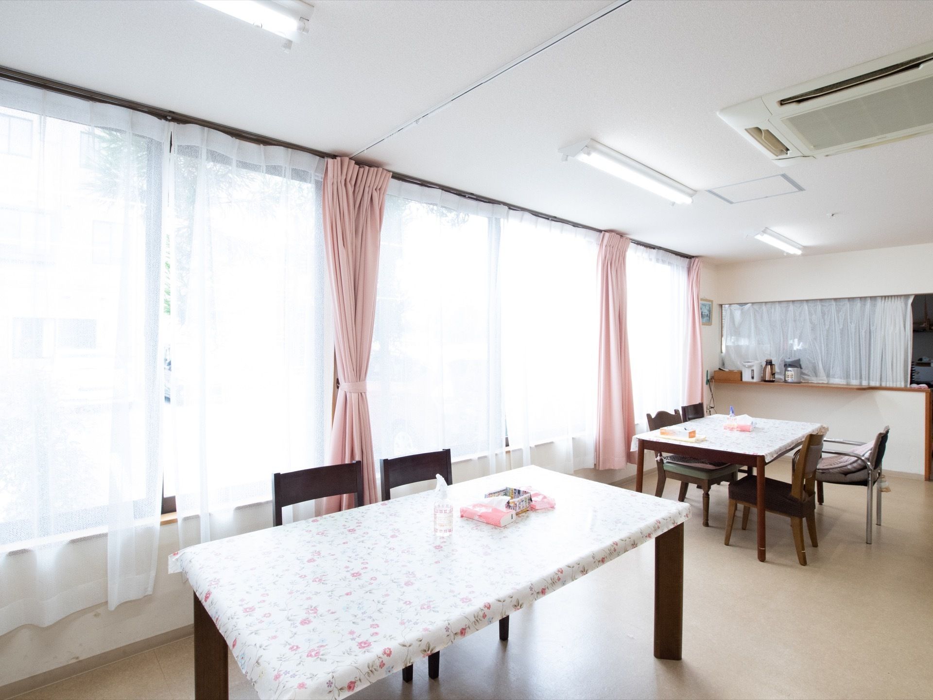 高い窓からは自然光が十分に差込み、大変明るく開放的な空間である。ダイニングセットは車椅子でも自由に移動できるように配置している。