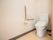 車椅子対応の広いトイレがある。壁にはL字型の手すりが設置されていて、その横には緊急通報装置も付いている。