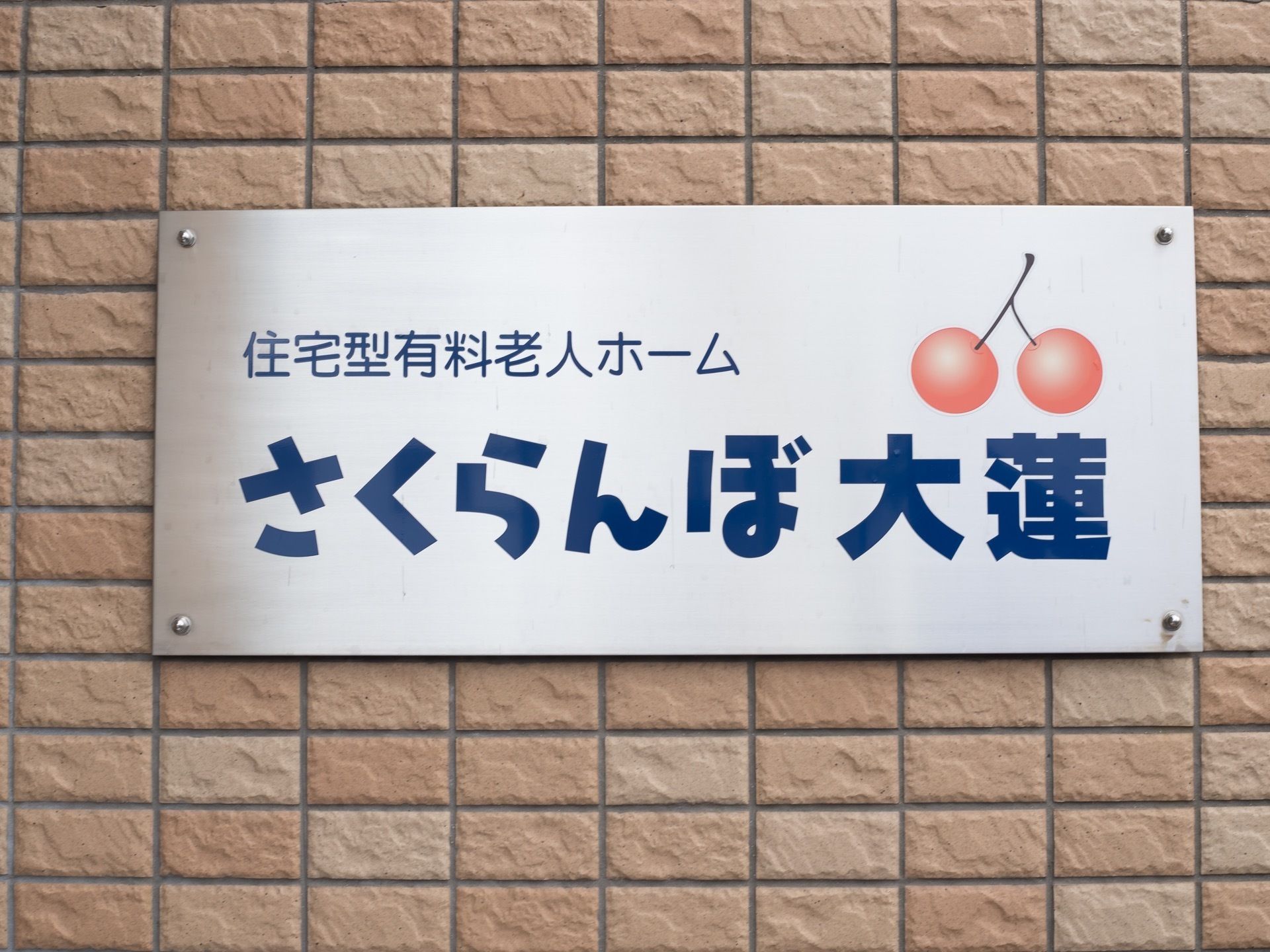 施設の外に看板を取り付けている。施設名からイメージされるさくらんぼをあしらったデザインを表示している。
