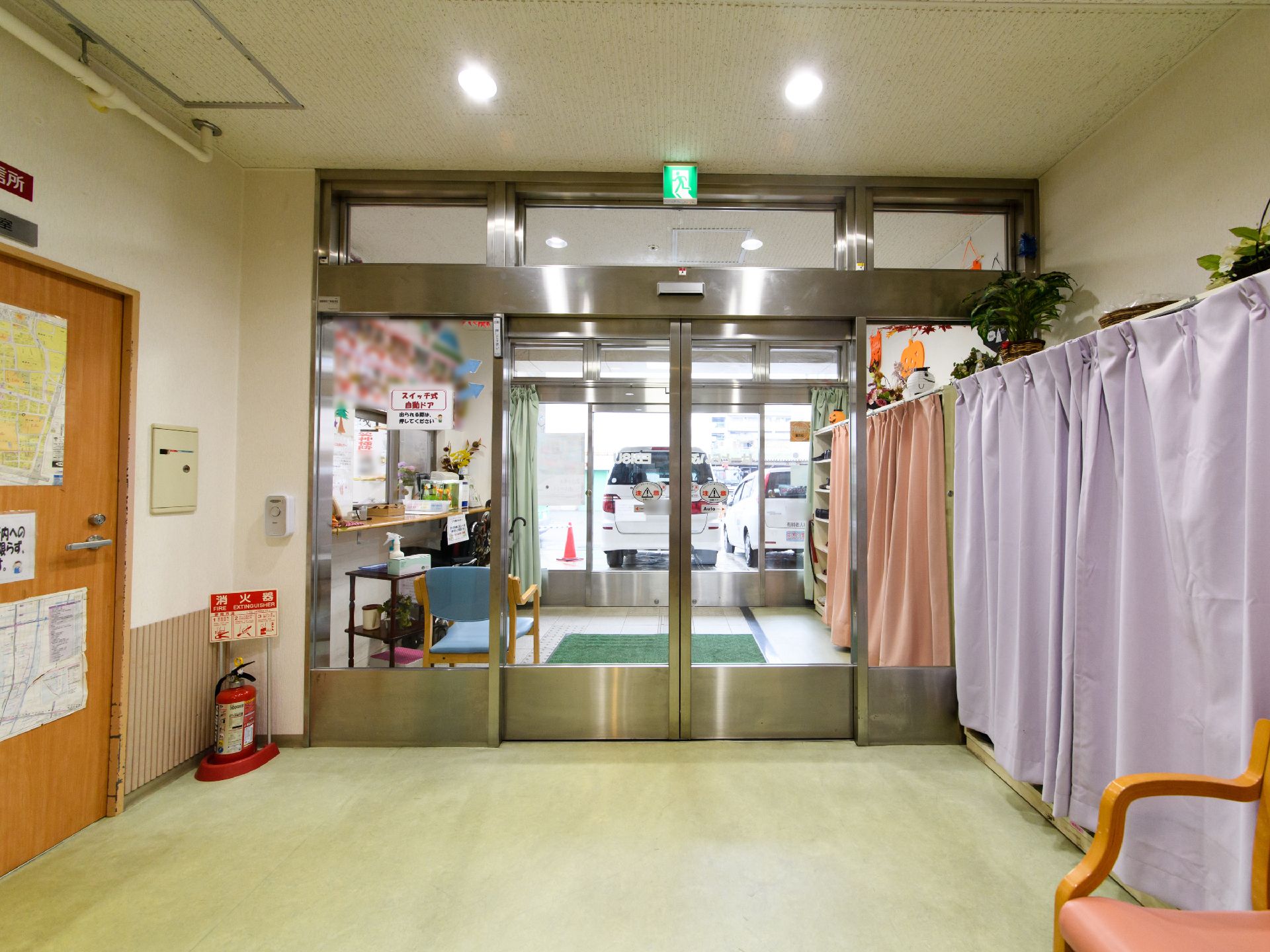 施設の入口は、ガラス製の自動ドアである。入館して左手には、カーテン付きの下駄箱が並んでいる。その上に、観葉植物が置かれている。
