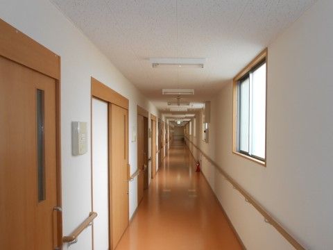壁に手すりが設置され、消火器が置かれた見通しの良い居室前の廊下