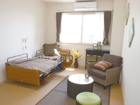 窓やエアコン、補助ホルダー、介護用ベッドが設置された居室