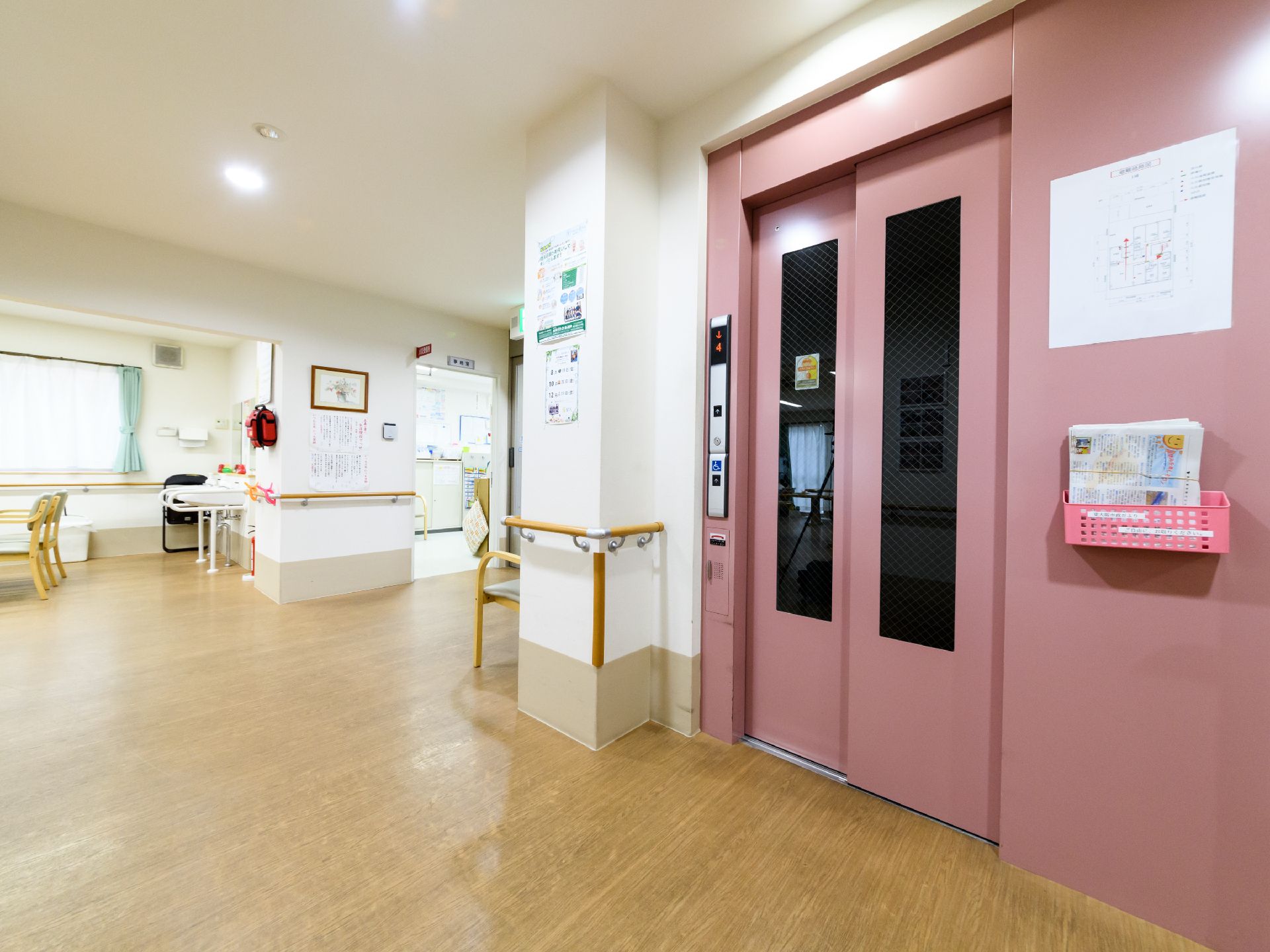 共用廊下は、天井よりの壁は白く、床よりの壁はベージュ系と柔らかい色が使われている。エレベーターのピンク色も周囲に馴染んでいる。