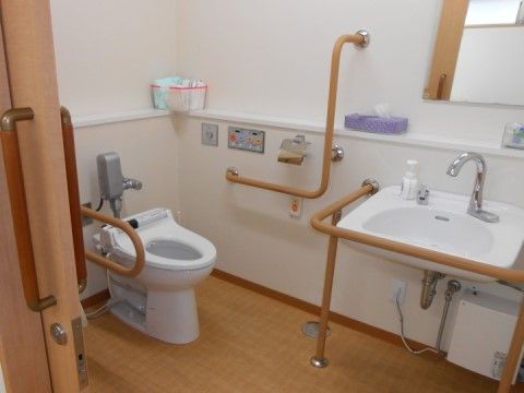 温水洗浄便座やセンサー付き洗面台があり、周囲に手すりが取り付けられたトイレ空間