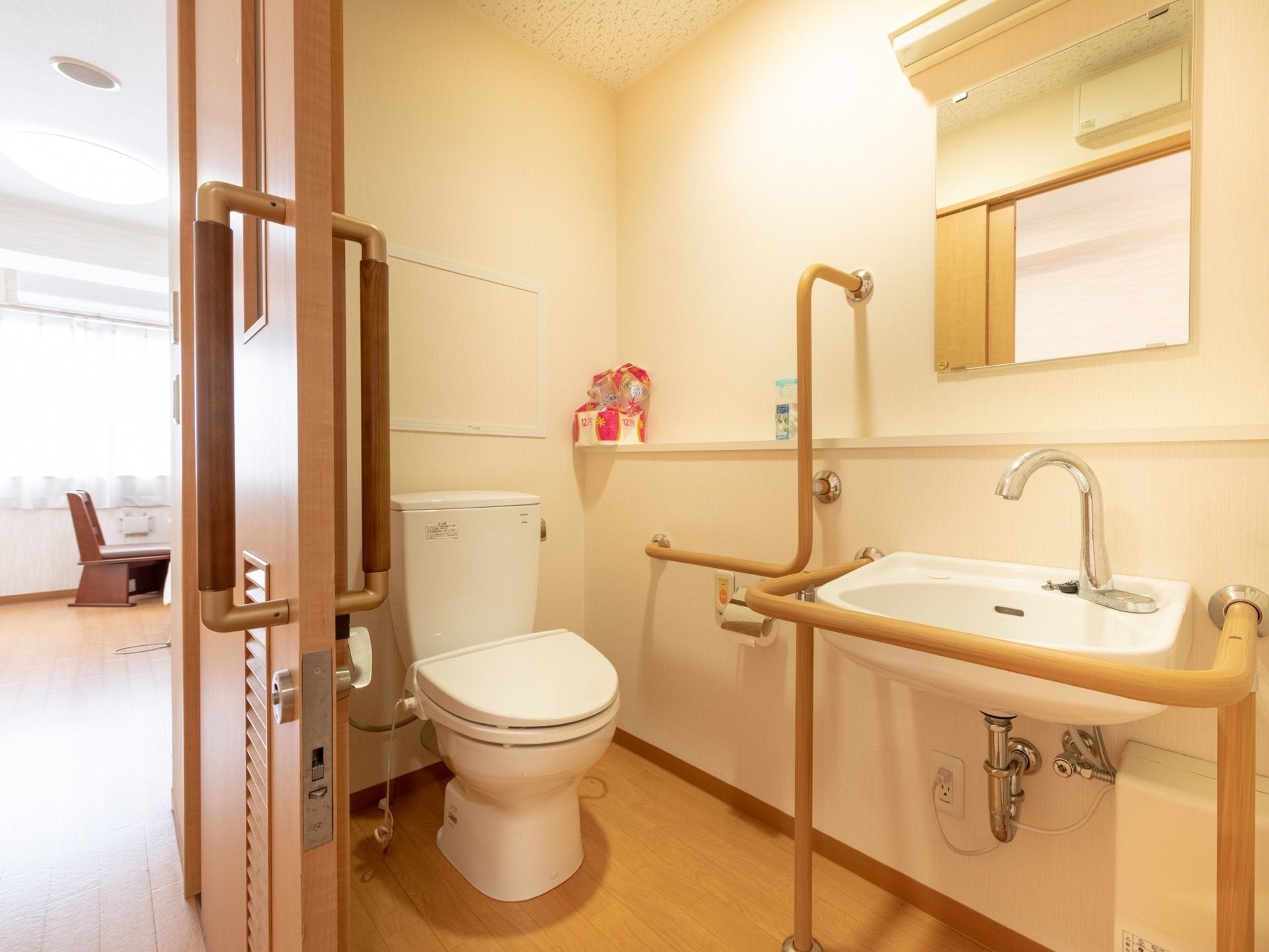 居室に設けられたトイレ。扉には引き戸が採用されている。便器や手洗い場のまわりに手すりが設置されている。