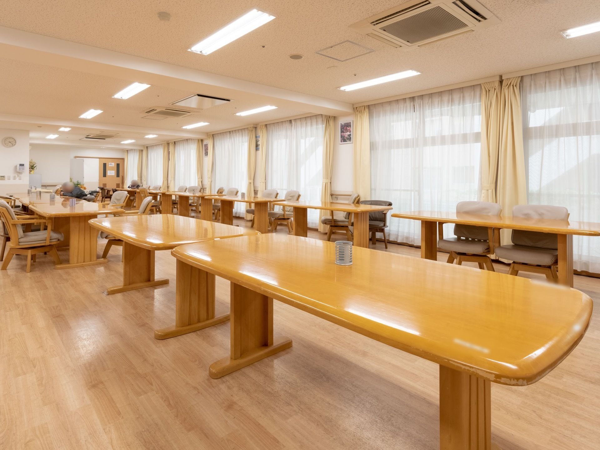 ベージュの天井に茶色のフローリングの床である。大きな窓にはレースと黄色のカーテンが備えつけられている。