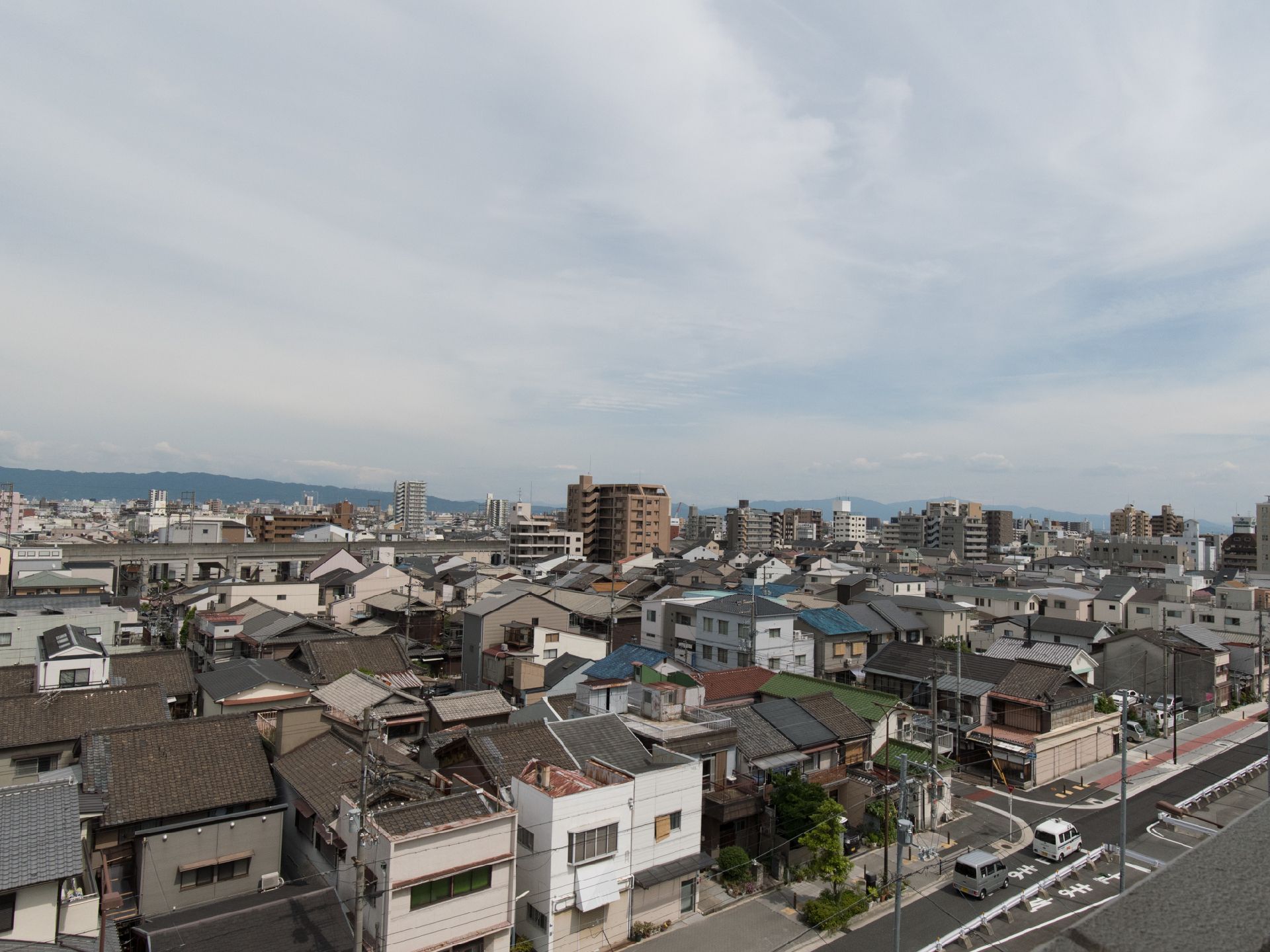 施設の周辺環境の画像。住宅が通り沿いに密集しており、遠くには高いビルもみられる利便性の良い立地となっている。
