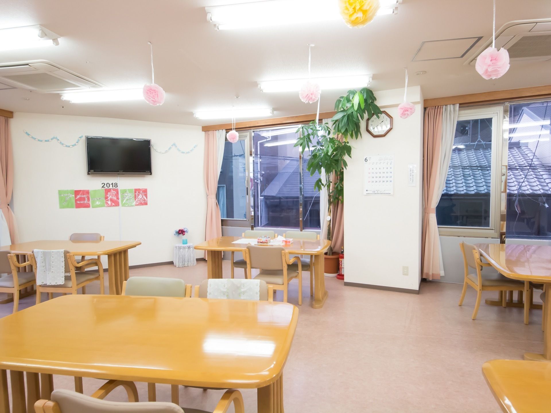 広々した共用スペースに壁掛けのテレビが備え付けられている。遠くの席からも観賞できるよう、工夫して設置している。