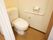 トイレには白いカーテン扉が取りつけられており、壁にはトイレットペーパー掛けと手すりが取りつけられている。