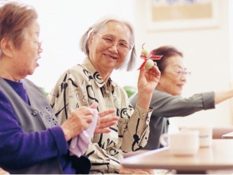 ３人の女性の入居者様が集う中、こちらに微笑みかけている中央の入居者様