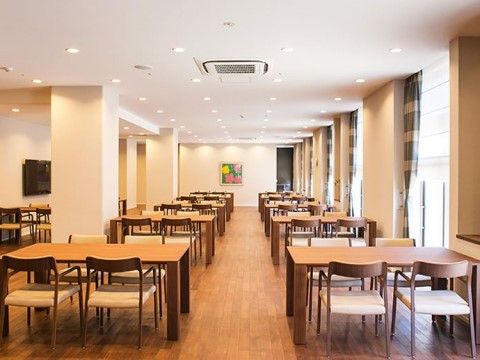 室内には4人掛けのテーブルと椅子が並べられている。天井には空調設備が設置され、テレビや絵画が壁にかけられている。