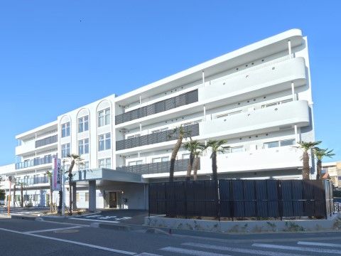 青空を背景にエントランスポーチを完備している白い４階建ての施設