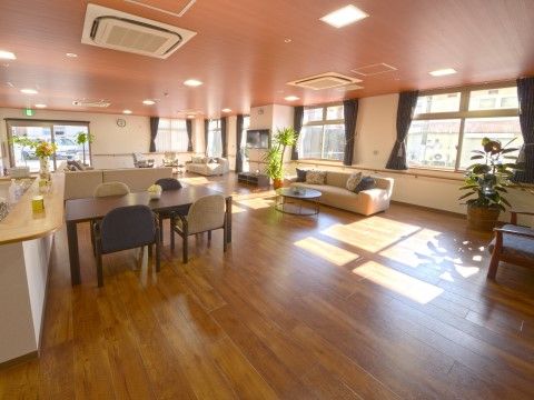 窓から自然光の差し込む明るいリビングである。広い空間に、ダイニングテーブルやソファがゆったりと置かれている。