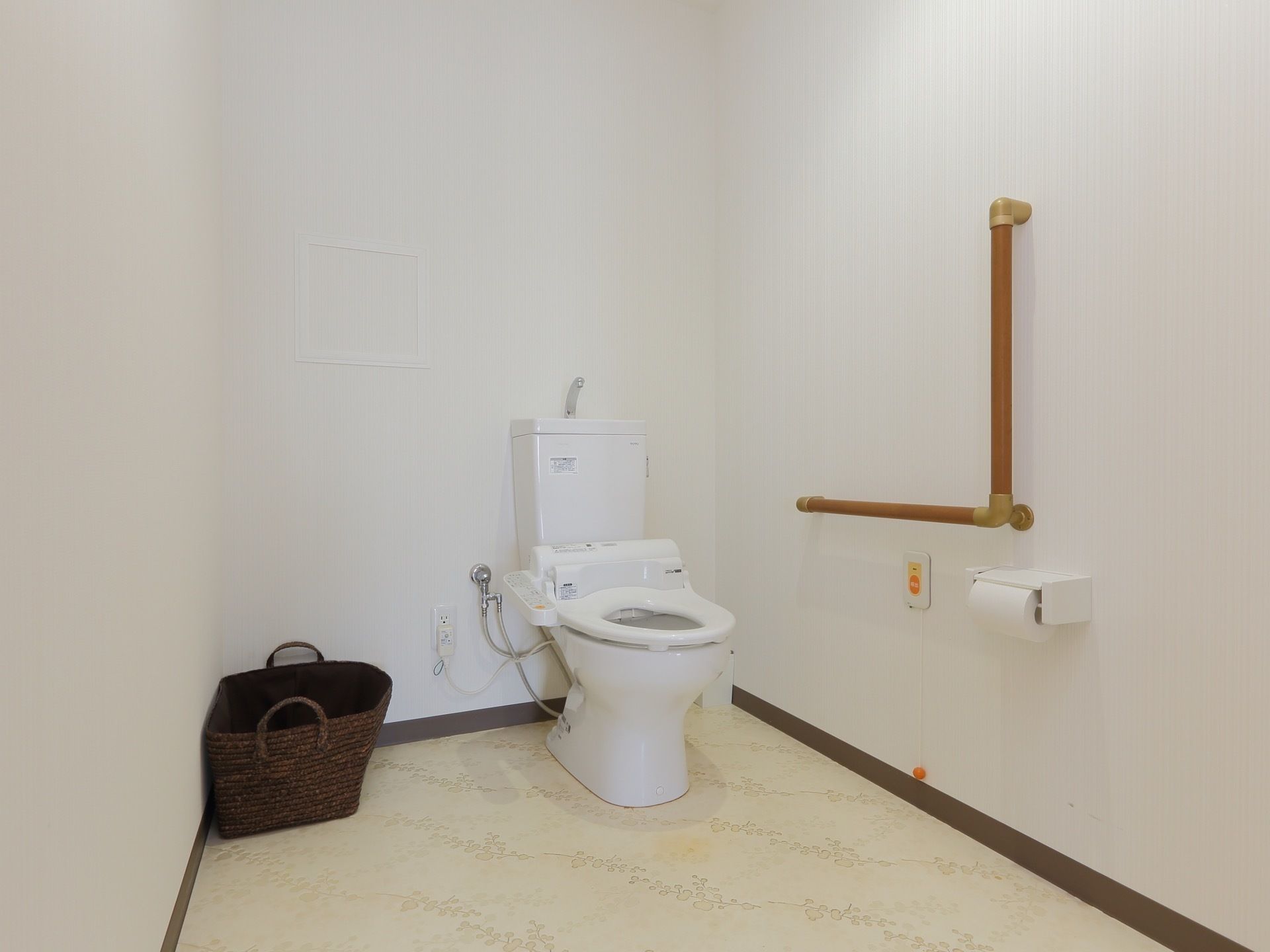 トイレの便座にはふたがない。壁にはくの字に手すりがついており、ナースコールの紐は床近くまで伸びている。