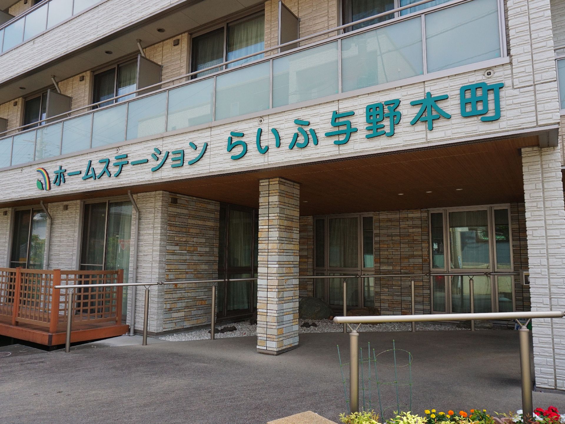 金属製の大きな手すりが取り付けられ、頭上に施設の名称が書いてある玄関