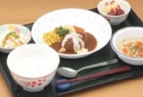 黒いプレートにお箸とスプーンと共に並べられている献立