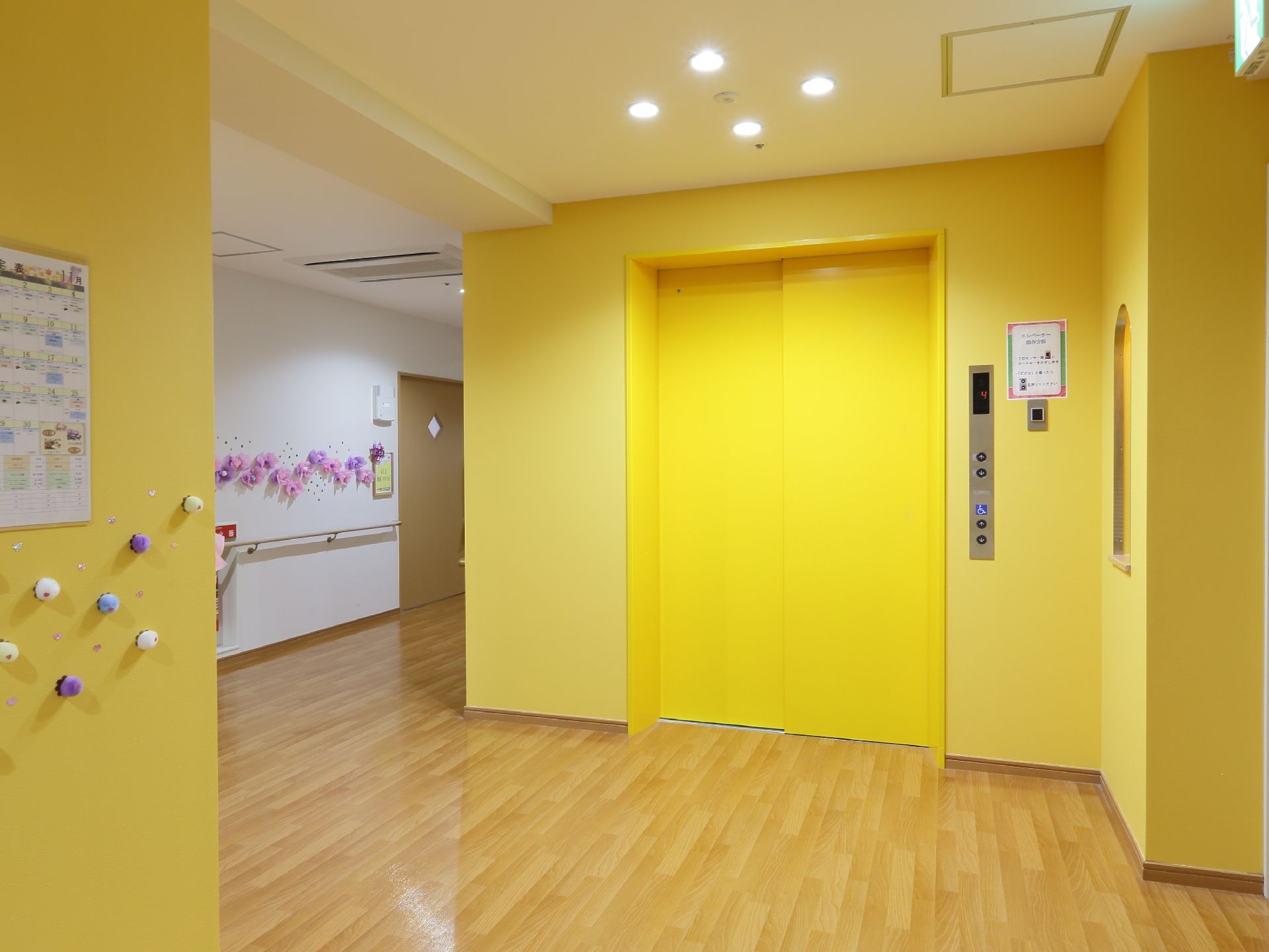 淡いクリーム色の壁にマッチしたイエローのエレベーターが設置されており、エレベーターホールは広々としている。