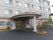 外壁にグレーとレンガをあしらった洋館のような雰囲気がある建物のアプローチにはオレンジの瓦屋根がある。