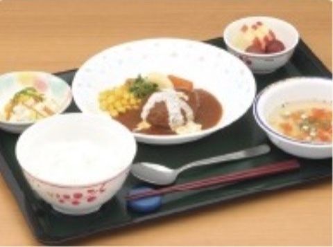ある日の食事は、ハンバーグステーキ、サラダ、スープ、白ご飯、果物である。栄養バランスの摂れた献立である。