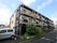 施設の建物は３階建てである。黒色と茶色を基調とした外観である。ベランダには、オレンジ色の入居者募集中の案内が掛けられている。