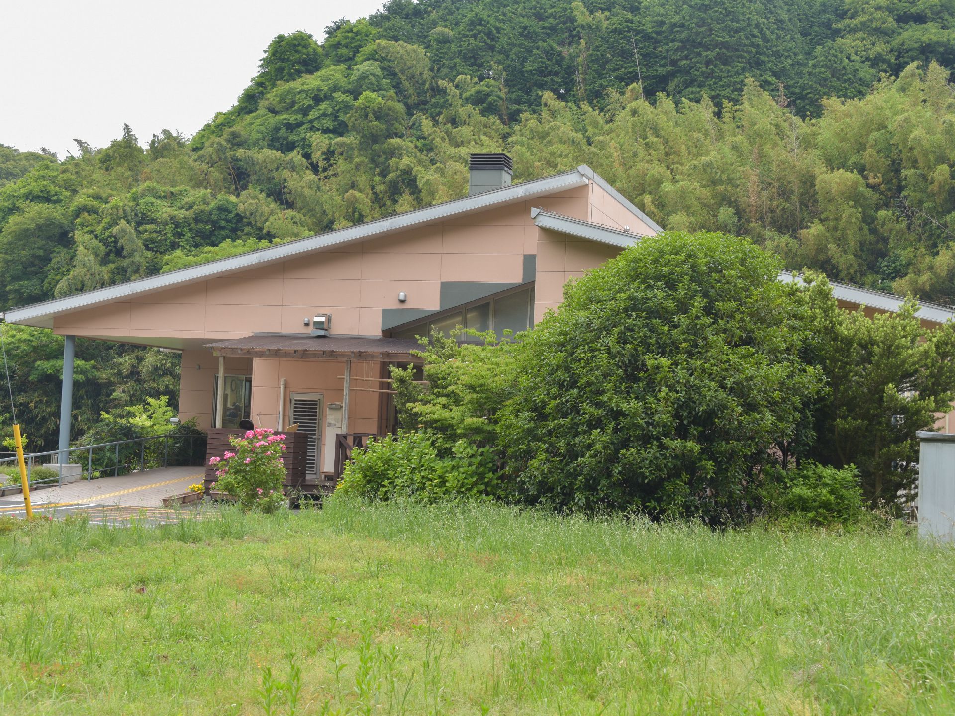 茶色の外壁の食べ物が、木々などに囲まれた場所に立っている。玄関前は手すりのついたスロープになっており、車椅子でも入館しやすくなっている。
