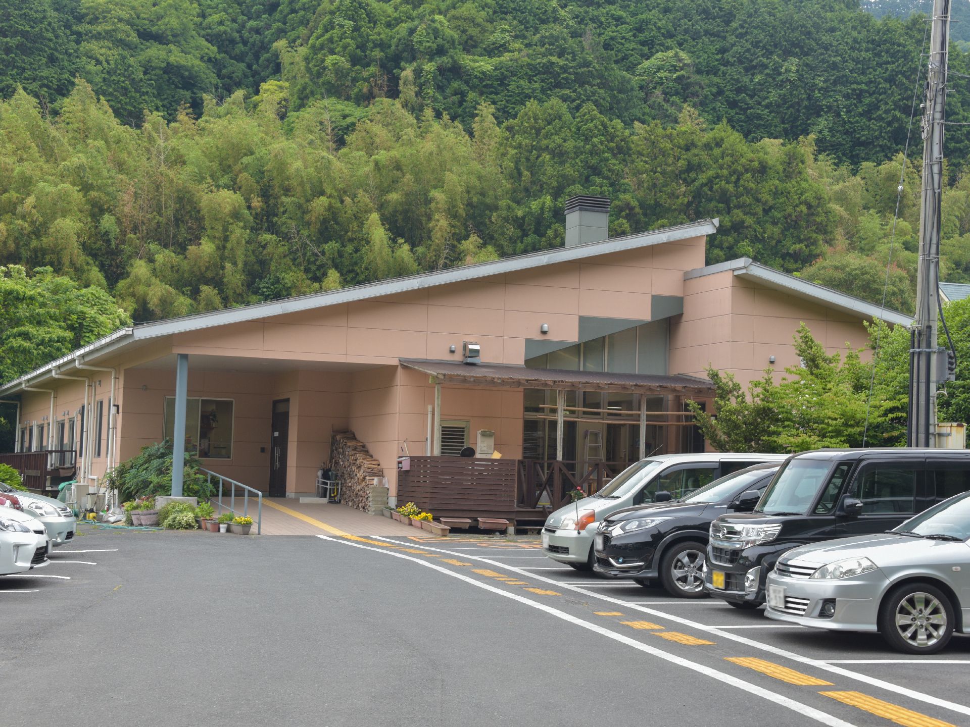 緑濃い森林を背景に駐車場スペースを完備している平屋建ての施設