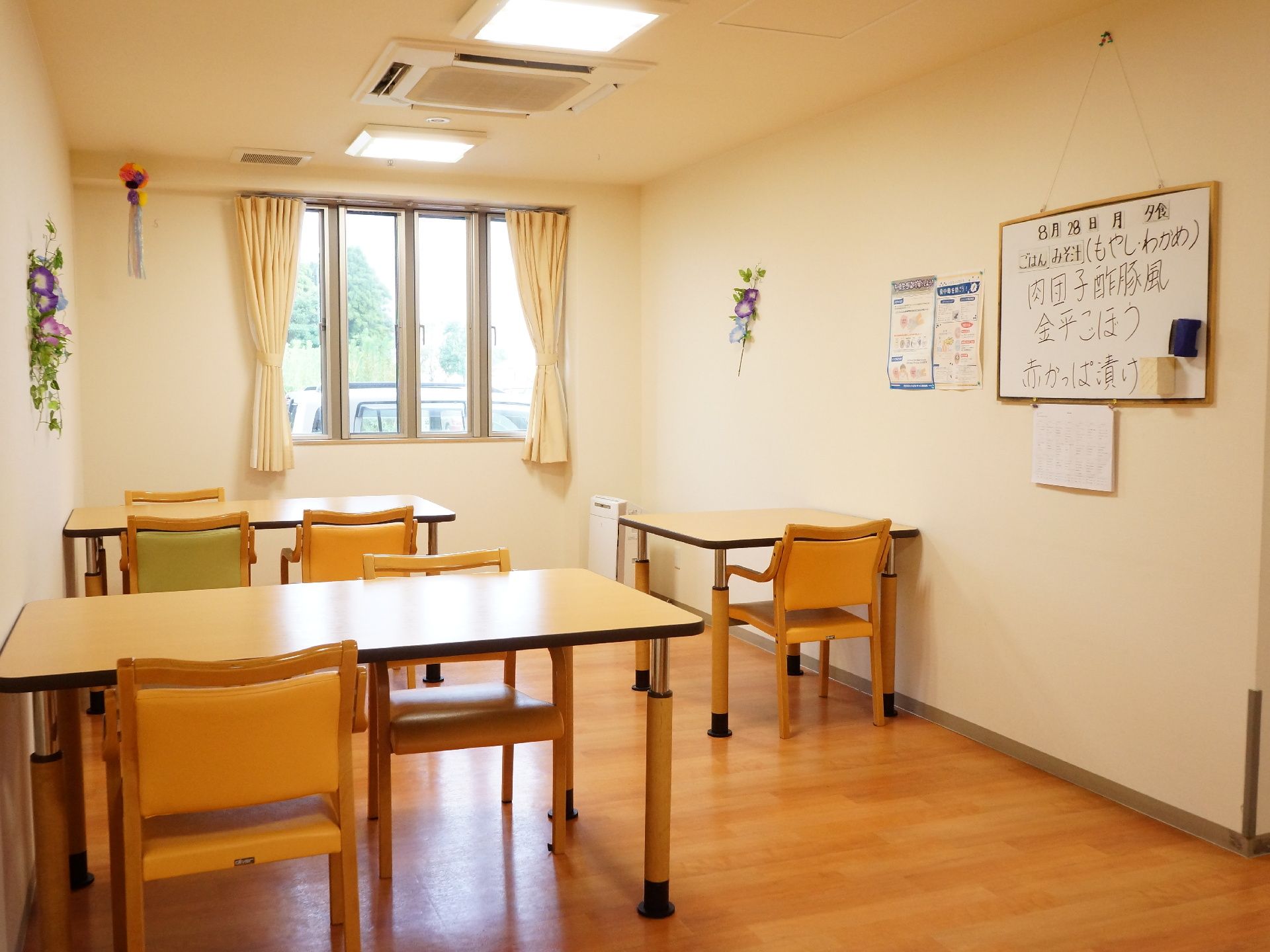 複数のテーブルが置かれた部屋の壁には、この日の夕食の献立が書かれた大きなホワイトボードが設置されている。