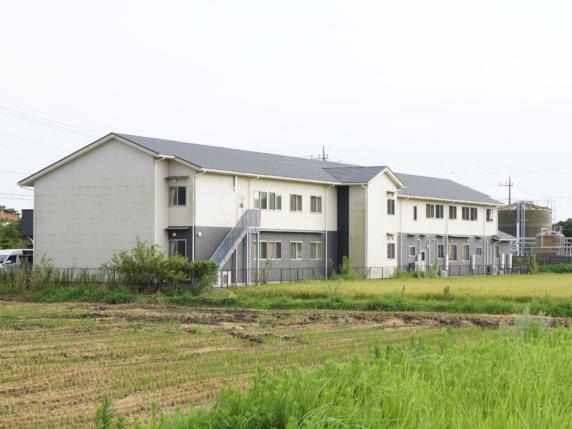 施設の裏には田んぼが広がっている。建物の裏手には非常時などに使用する地上と2階とつなぐ外階段がついている。