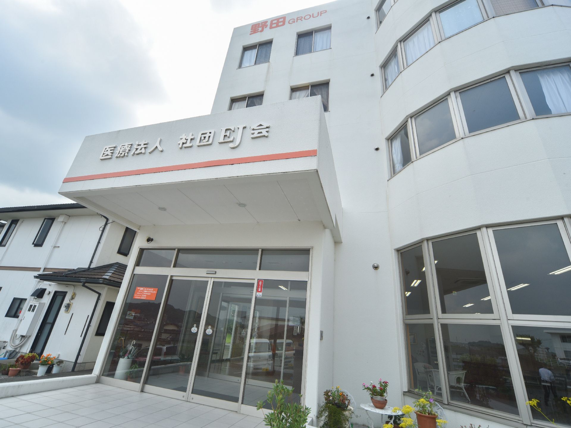 施設の入り口はガラスの自動ドアで、左右と上部もガラス張りになっている。上に四角い天井があり、前面には施設名が表示されている。