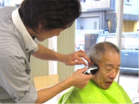 訪問理美容で男性の入居者様に施術を行っている男性理容師