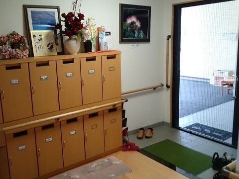壁に手すりが設置され泥落としマットが敷かれた施設玄関