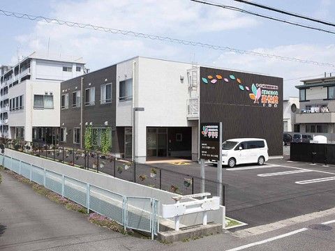 壁面に施設名称とロゴマークが明記されたツートーンカラーの２階建て施設外観